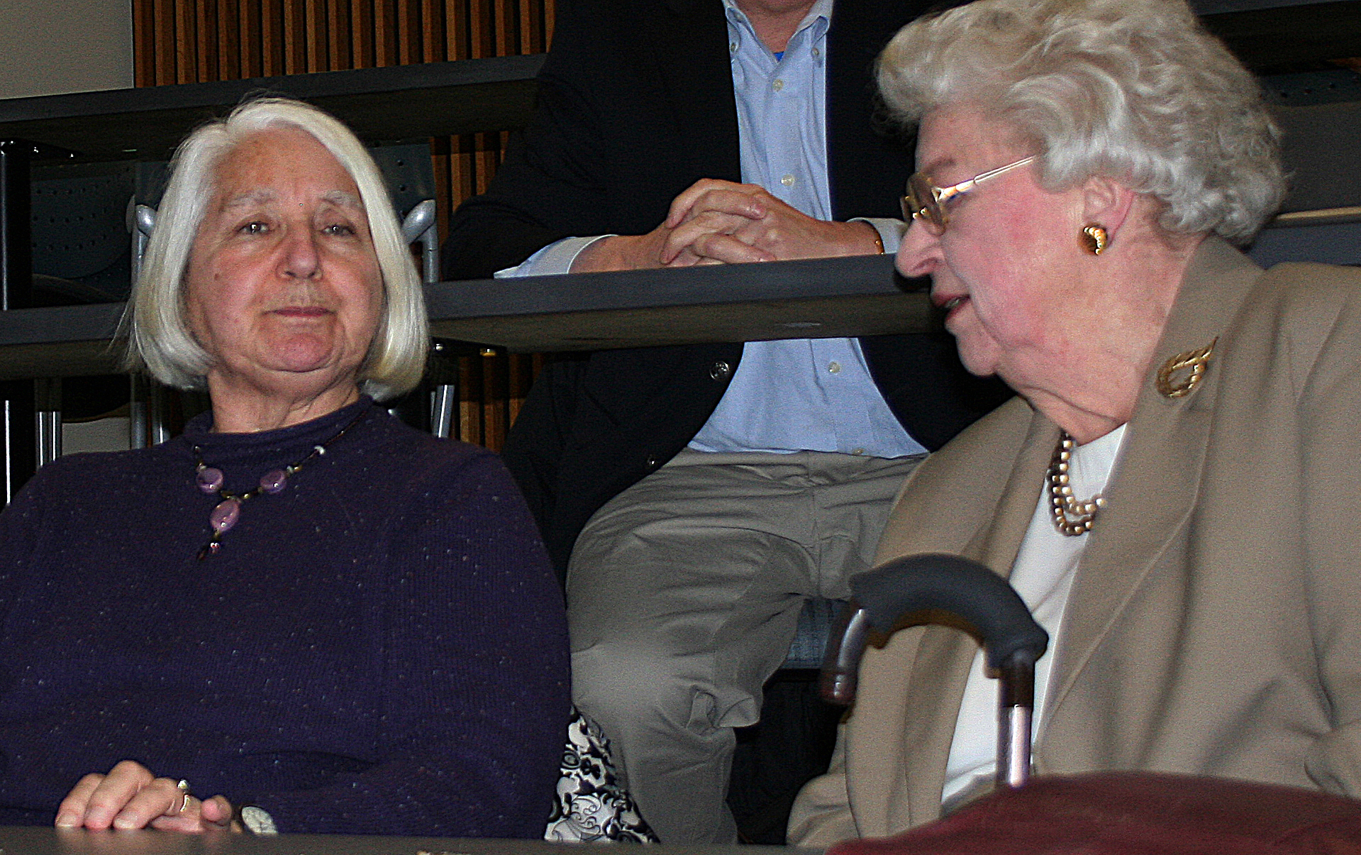 Two older women sitting in an auditorium. 